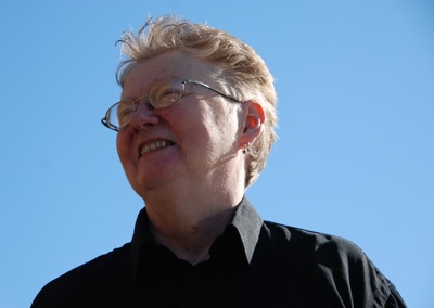 Head and shoulders colour photograph of Julie Newman, shot against a blue sky.