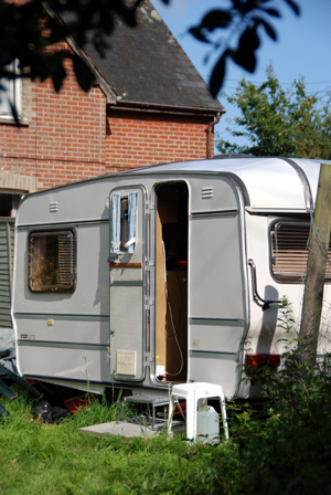 Colour photograph of the outside of the caravan, with the door open.