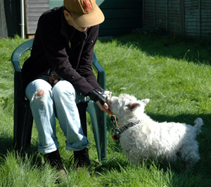 Colour photograph of me sitting in a plastic chair on the grass, with a Westie putting some keys into my hands.