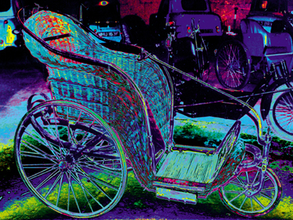 Photograph of an old-fashioned 'bath' (wheel)chair, made from wicker. The colours have been distorted to become bright purples and greens.